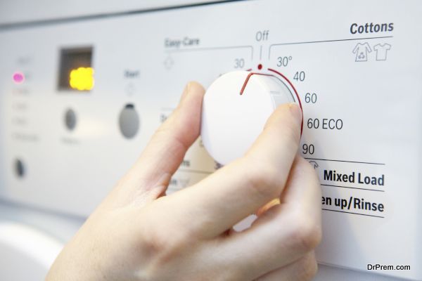 Woman Selecting Cooler Temperature On Washing Machine To Save En