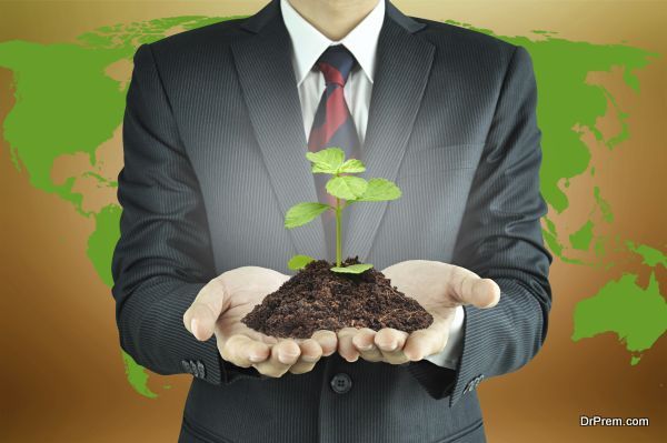 Businessman holding green seedling with soil