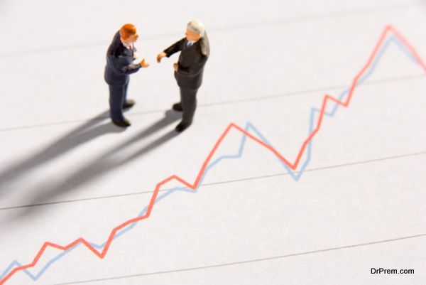 Figurines Of Two Businessmen Shaking Hands On A Line Graph