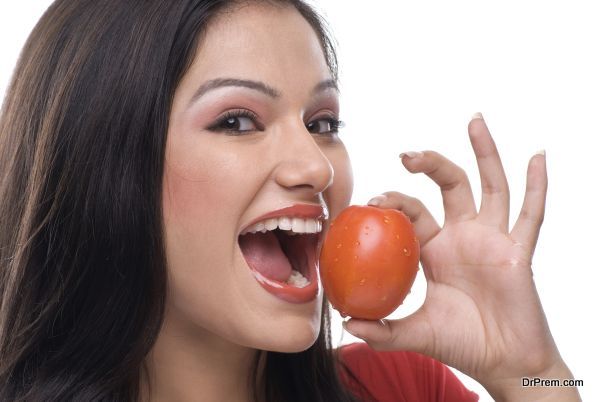 Woman about to eat a tomato