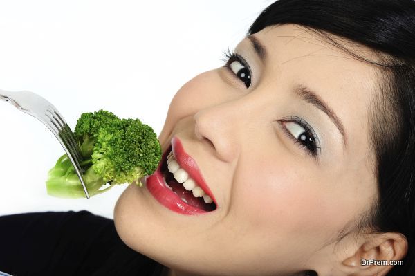Beautiful young asian girl eating broccoli