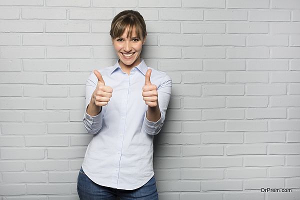 Happy Woman Showing Thumbs Up Sign isolated over a wall