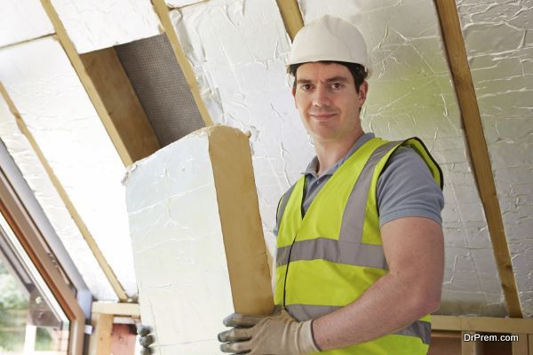 Builder Fitting Insulation Boards Into Roof Of New House