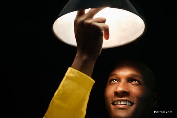 African man looking up and touching light bulb