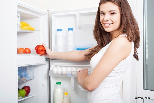Woman taking pepper from fridge
