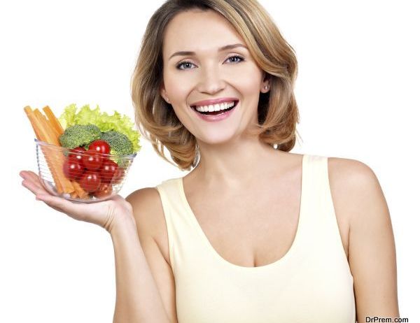 Portrait of a young smiling woman with a plate of vegetables - isolated on white.