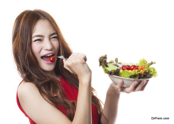 Young asian woman holding and eating fresh vegetable salad on white background