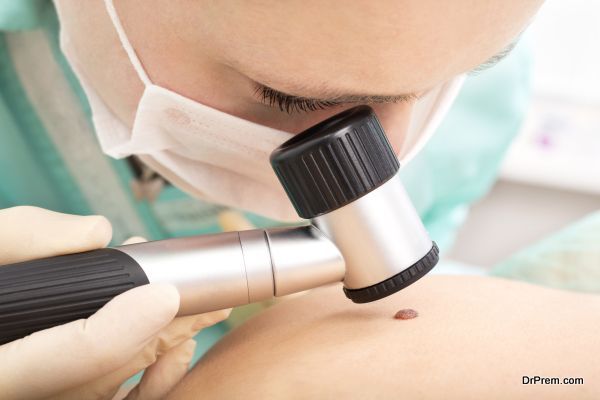 Dermatologist examines patient birthmark with dermatoscope