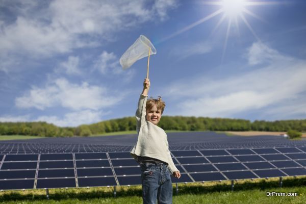 Portrait of boy holding up net to catch sunbeams in front of solar panels