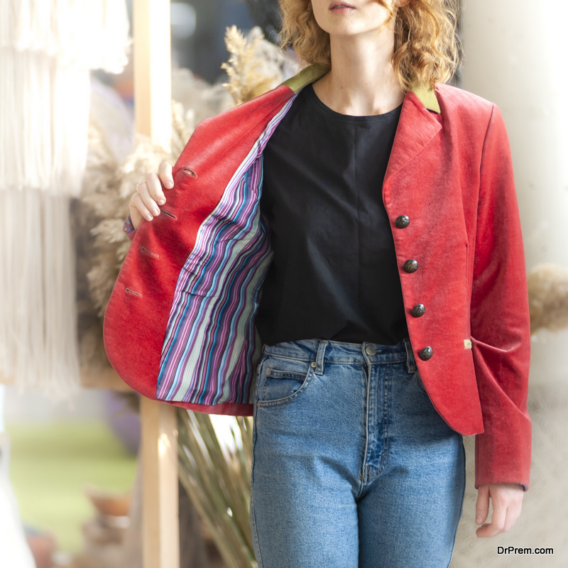 Redhead girl with curly hair is standing and demonstrating her red velvet blazer