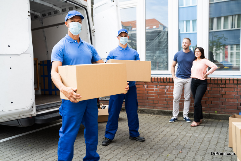 Blue Delivery Men Unloading Package From Truck With Face Mask