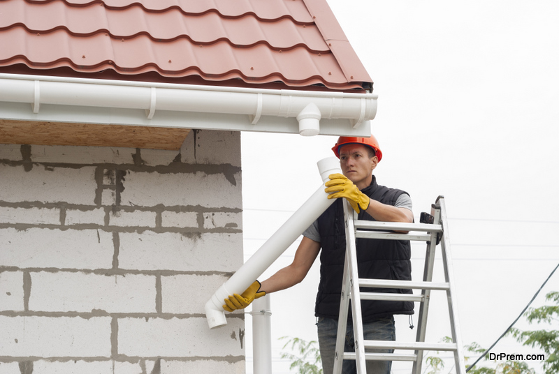 Trabajador de la construcción instala el sistema de canalones en el techo